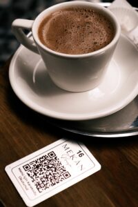 Restaurant tabletop QR code menu sign with updated digital menu displayed on a phone