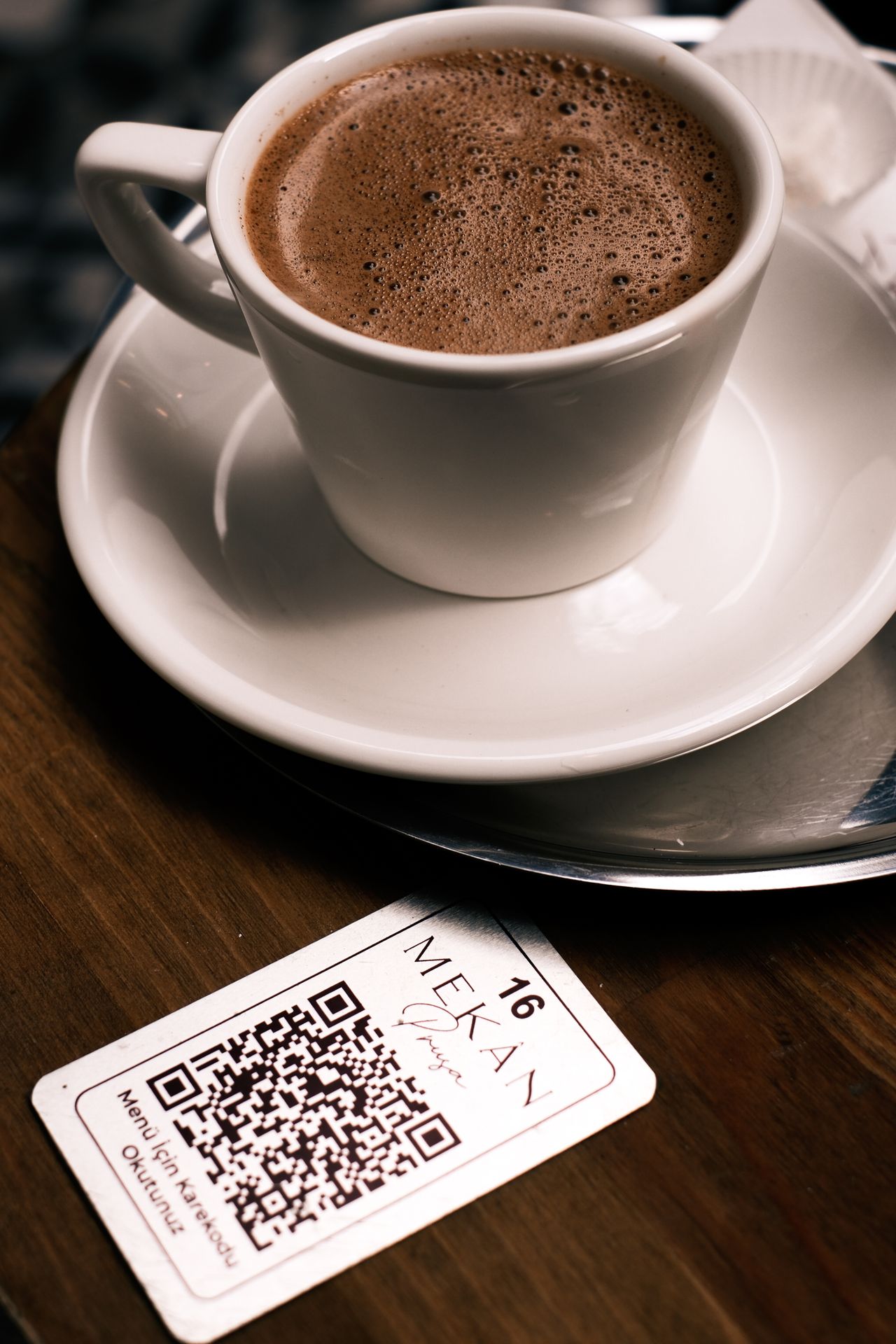 Restaurant tabletop QR code menu sign with updated digital menu displayed on a phone